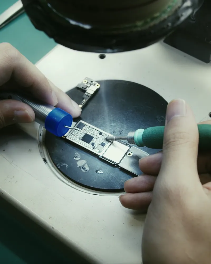 Técnico soldando componentes em uma placa eletrônica com ferro de solda