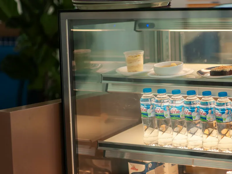 Expositor refrigerado com garrafas de água e doces em uma cafeteria